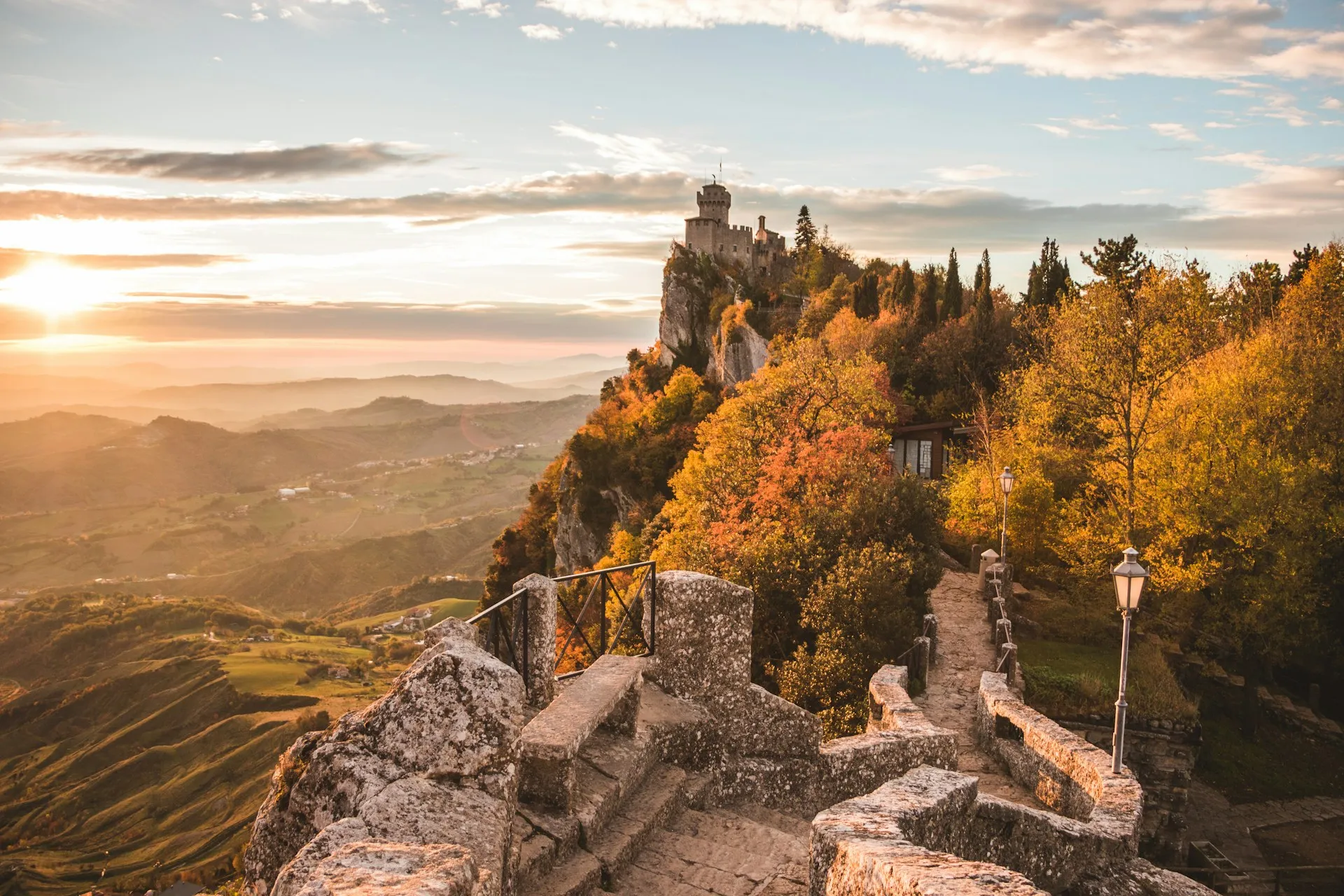 San Marino's tower on its cliff, autumn slopes falling away to the valley in the low sun